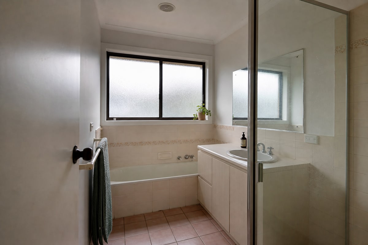 An older cream-tiled bathroom before renovation